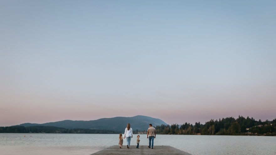Family on lake dock with sunset background