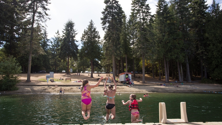 Girls jumping off dock into lake