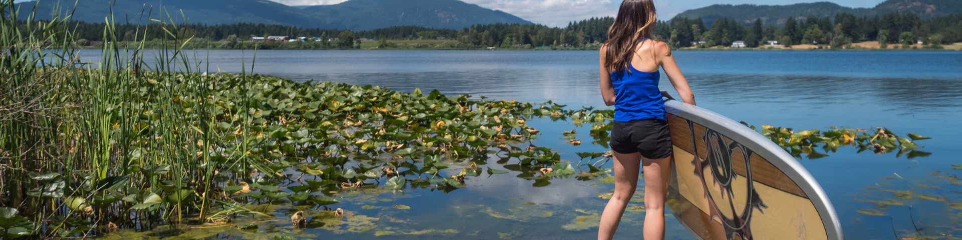 Woman with paddleboard standing at edge of lake