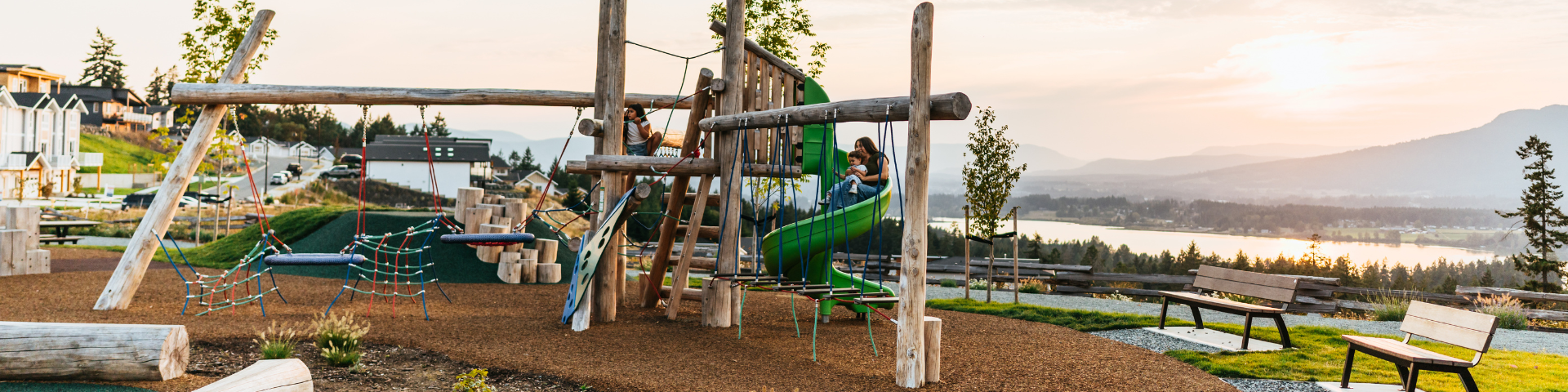 Family with small children playing at Seablush Park playground with Mt Prevost in the background