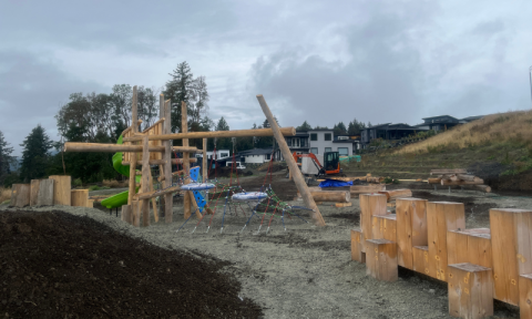 Natural playground being built, larger wooden structure with spiral slide