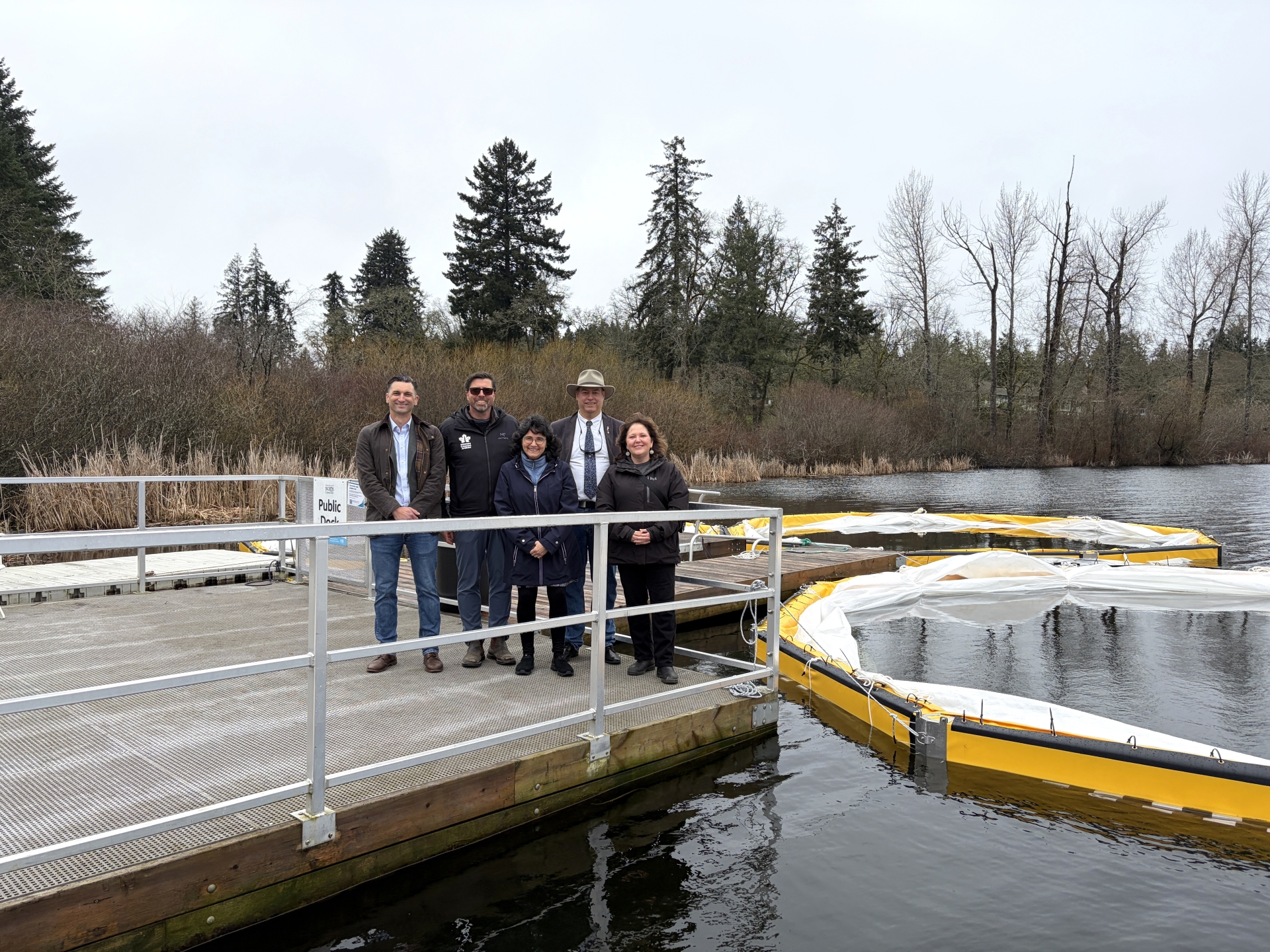 A group of people stand on a dock next to pens in the water that will be used for water quality testing
